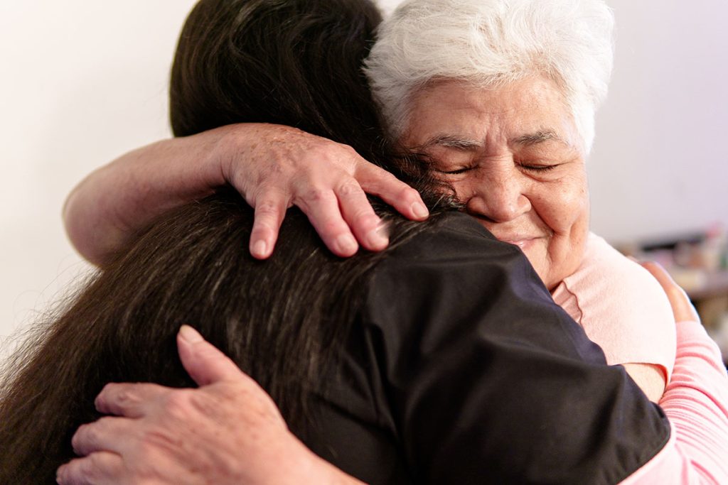 Nurse hugging elderly patient, providing comfort and care